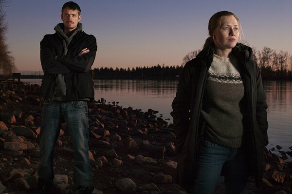 Homme et femme debout près de la rivière au coucher du soleil