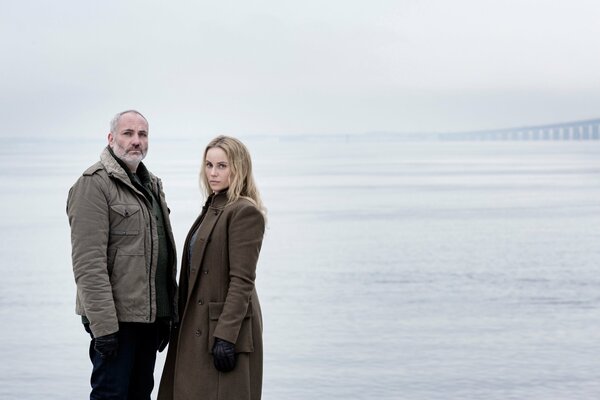 Ein Mann und eine Frau stehen warm gekleidet im Meer