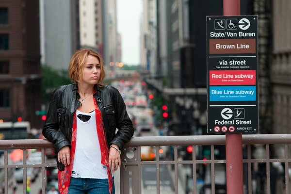 A girl in a leather jacket is standing on the bridge