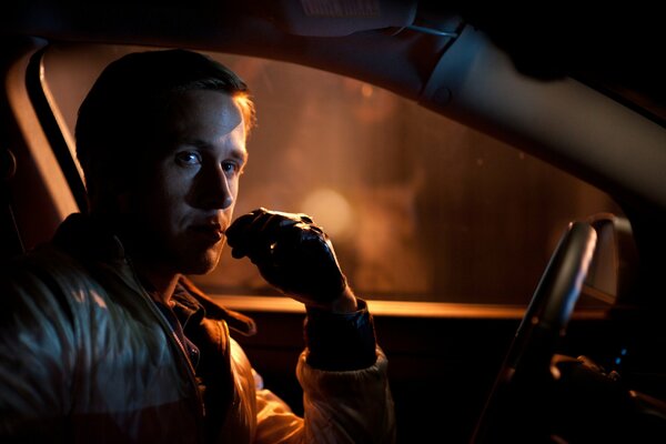 Ryan gosling sits behind the wheel of a car