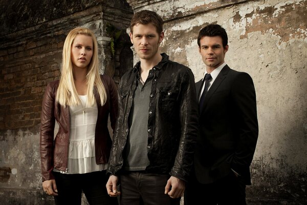 Stylish portrait of three people on a wall background