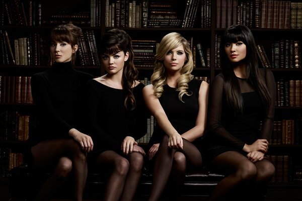 Girls are sitting on the background of shelves with books