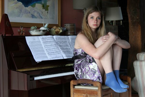 Ragazza seduta accanto al pianoforte