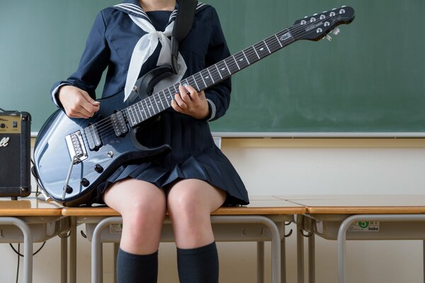 Ножки девушки, сидящей на столе с гитарой в руках