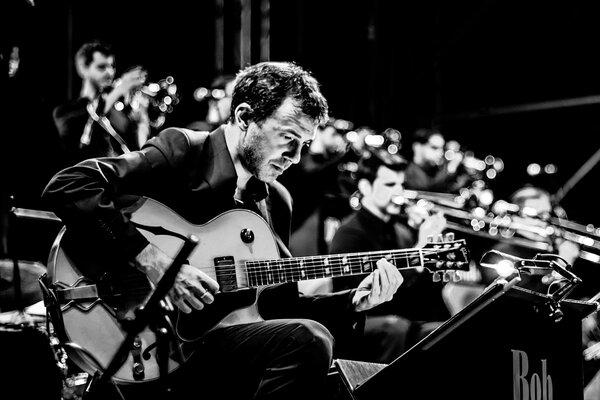 Foto de la orquesta con el guitarrista en primer plano