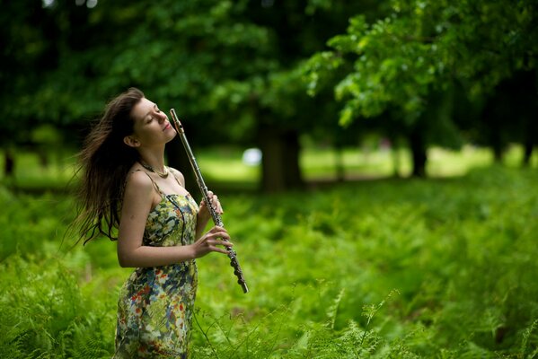 A girl plays a flute in the forest