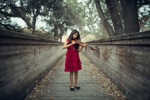 Chica violinista con vestido rojo jugando en la calle