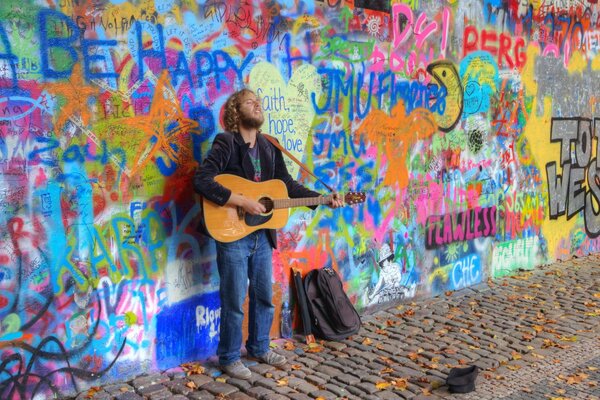 Musiker spielt Gitarre, während er an der Wand steht