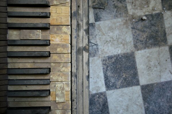 Old broken piano keys on a tile background