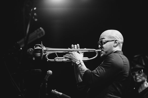 A musician plays the trumpet in the night light