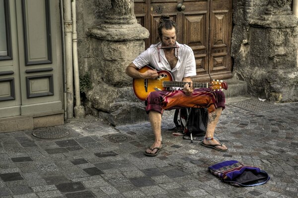 A street musician plays sitting on a chair