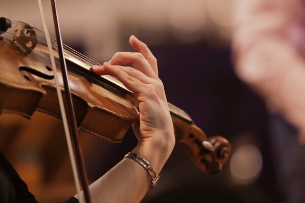 Hand, bow and violin on a dark background