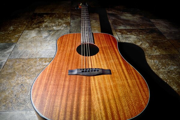 The guitar is lying on a brown tile