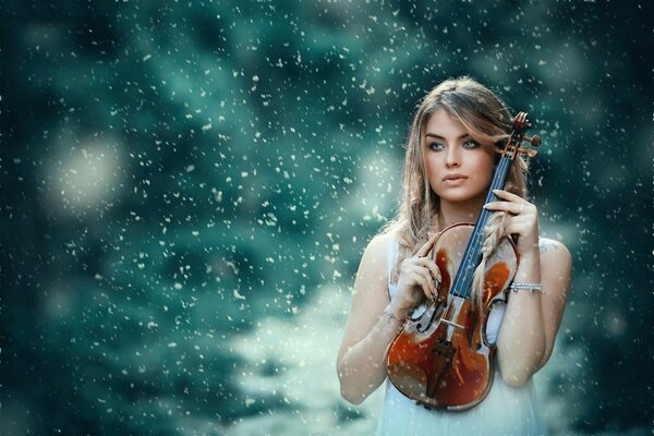 A girl with a violin on a background of snow