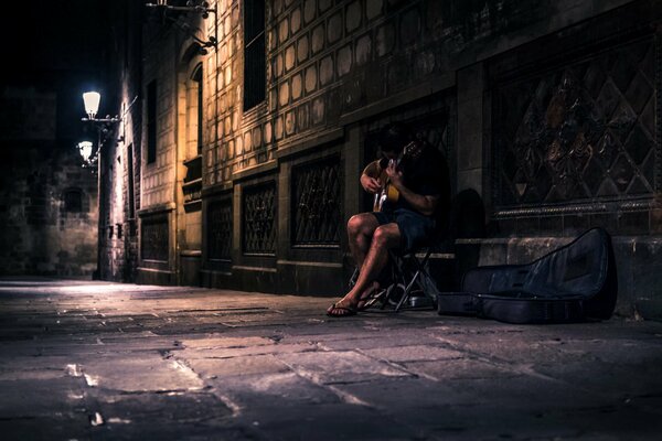 A man with a guitar on the street at night