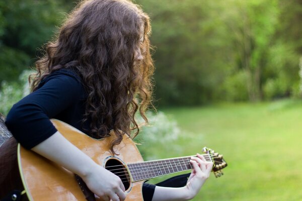 Chica en el campo con una guitarra en la mano