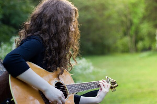 Девушка на поле с гитарой в руках