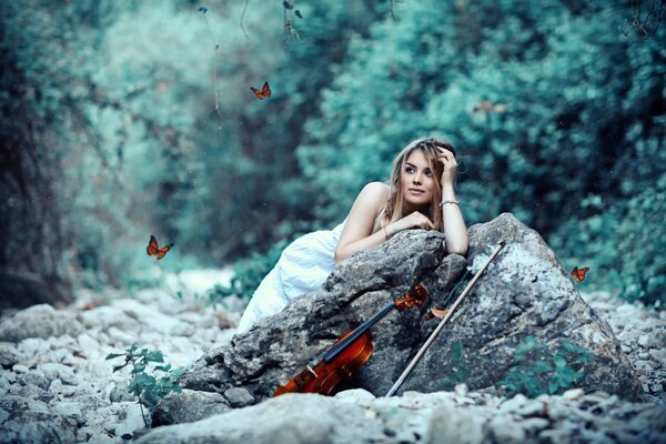 Beautiful girl on a rock with a violin