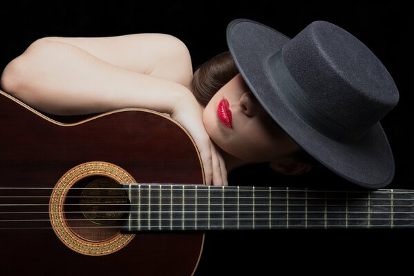 Ragazza in cappello con rossetto rosso e chitarra