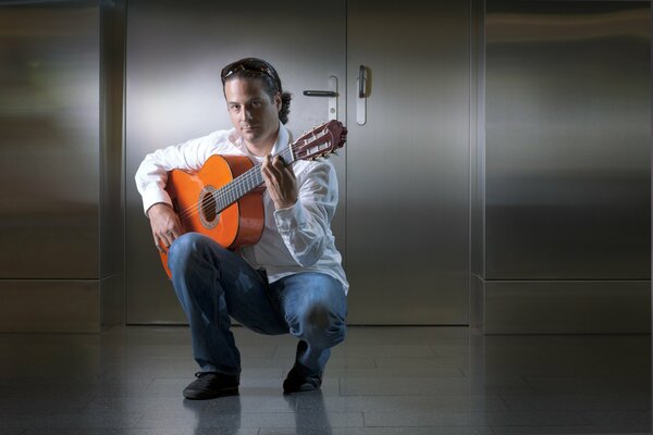El guitarrista David con camisa blanca y pantalones azules sostiene la guitarra