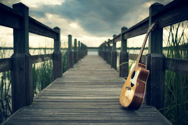 Guitar on the pier under a cloudy sky