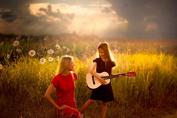 Im Sommer spielt ein Mädchen auf dem Feld für Mama Gitarre