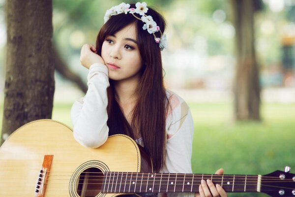 Chica en una corona con una guitarra en un vestido blanco