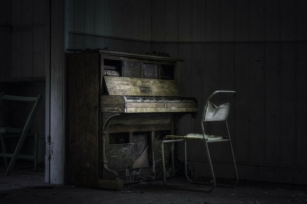Un antiguo piano y una silla en una casa abandonada