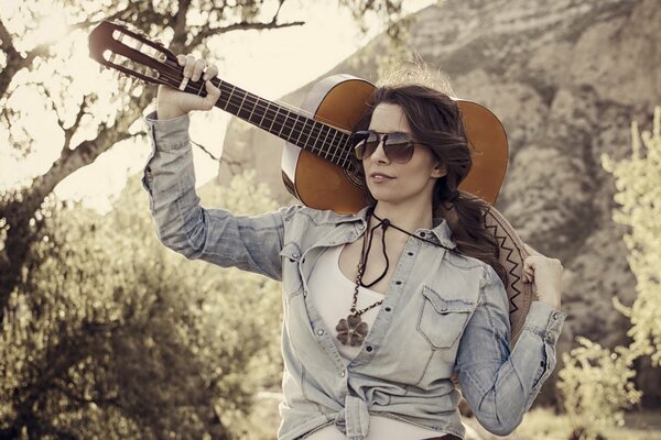 A girl with a guitar in her hand in the forest