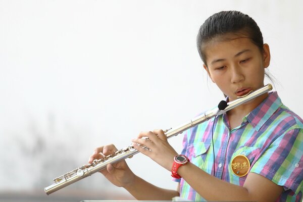 Азиатская девушка играет на флейте