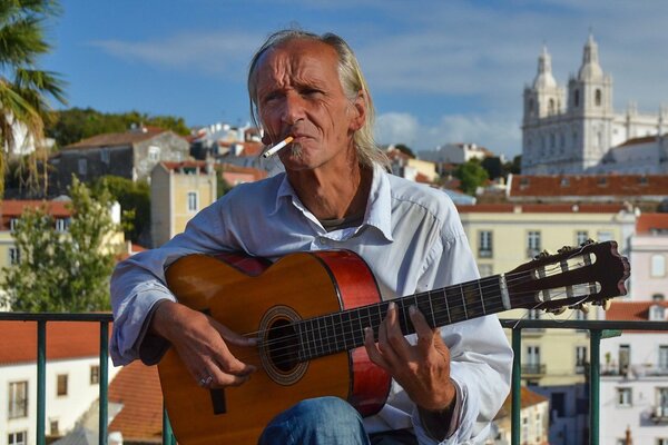 Un hombre con un cigarrillo toca la guitarra