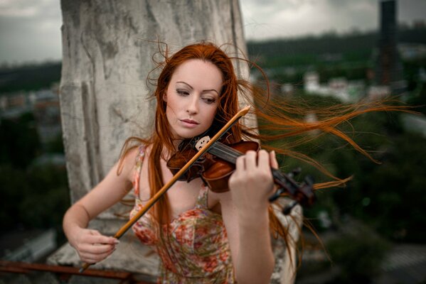 Rothaarige Mädchen spielt die Geige der Windmusik