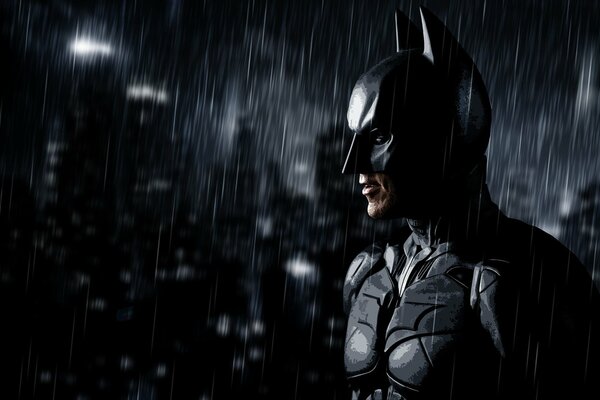 Batman stands in the dark in the rain