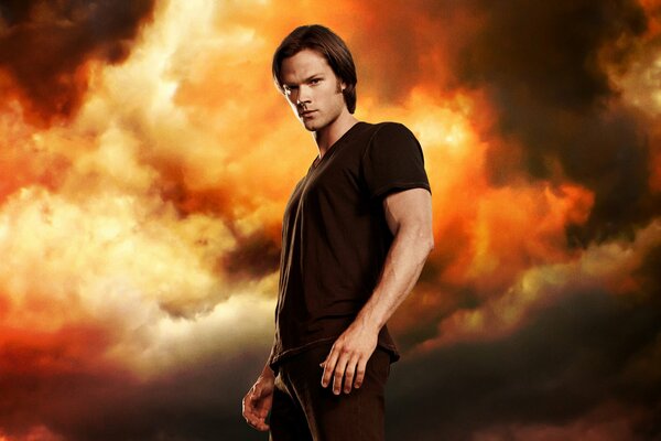 Sam Winchester de Supernatural se dresse sur un fond de ciel rouge