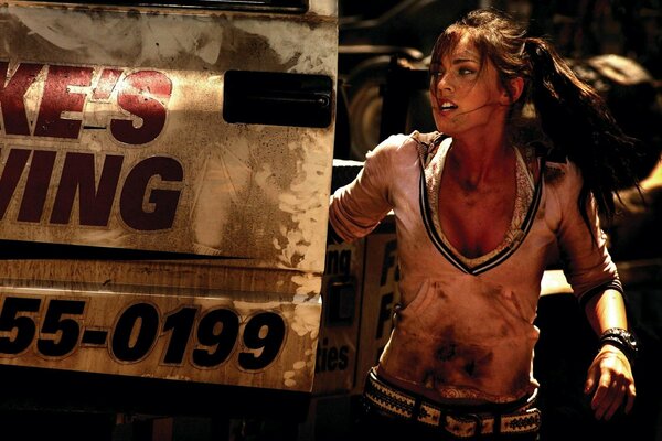 Megan Fox in the foreground running in a dirty T-shirt