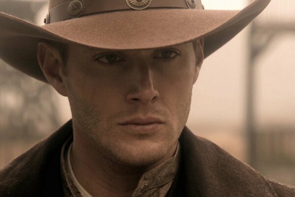Dean Winchester è in piedi come un cowboy con un cappello in testa
