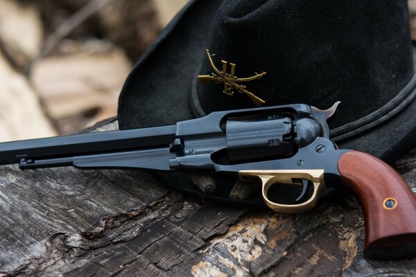 An 1858 revolver and a hat on a dry tree trunk