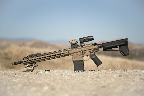 An assault rifle against the background of hills stretching away into the distance