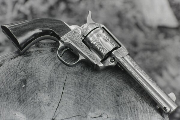 An antique revolver with patterns lying on a stump