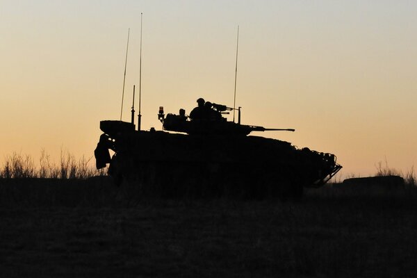 Silhouette of a tank and soldiers at sunset