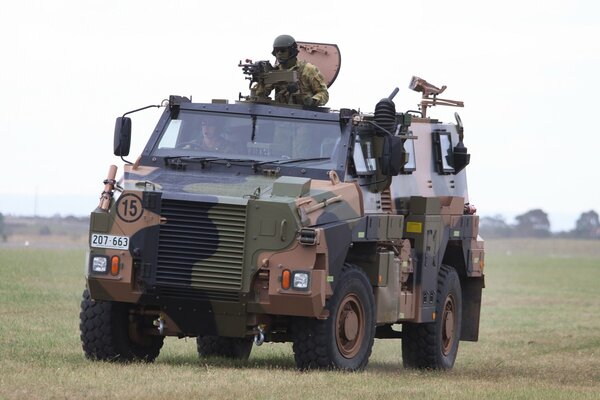 Soldiers ride across the field on an armored personnel carrier