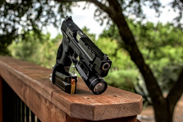 Pistola con linterna en la barandilla de madera