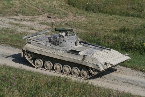 A combat vehicle is driving along a field road