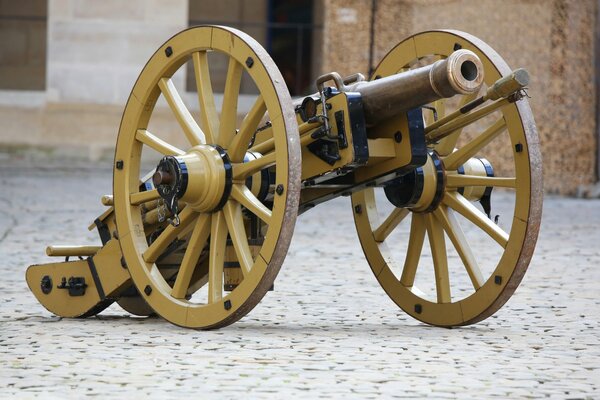 An artillery cannon stands against the background of a building