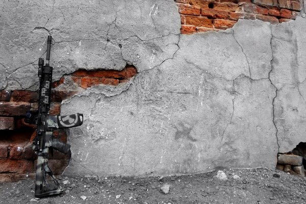 A black machine gun placed against a ruined wall