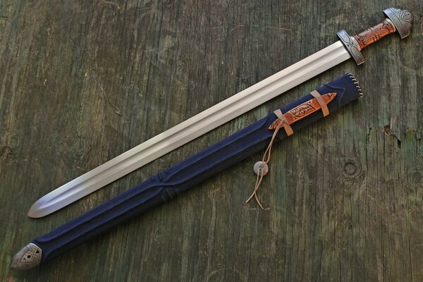 Una spada foderata poggia su una superficie di legno