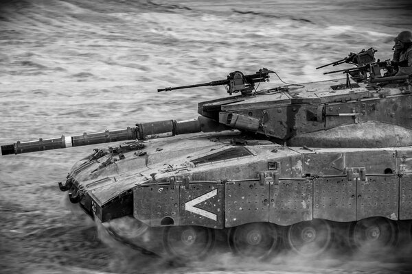 A black and white tank rides across the field