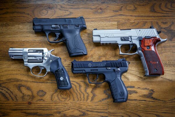 Cuatro pistolas de diferentes marcas en la superficie de madera