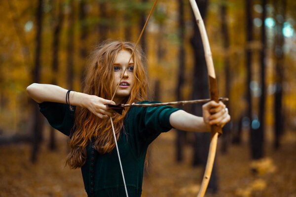 Ragazza con un arco sullo sfondo della foresta autunnale