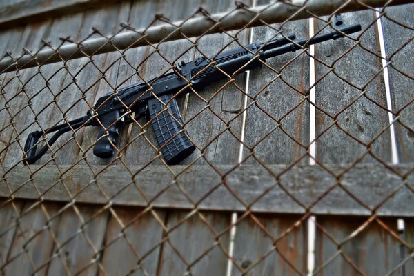 Zdjęcie strzelby za ogrodzeniem z siatki